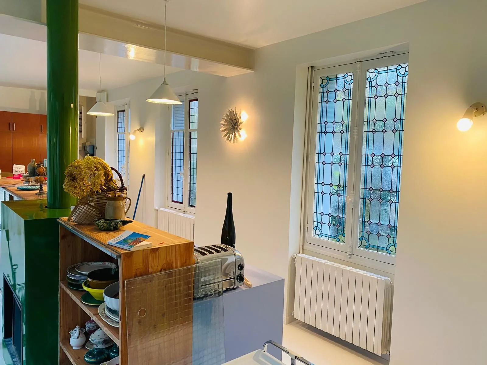 Cuisine ouverte avec vitraux, étagères en bois et radiateur blanc