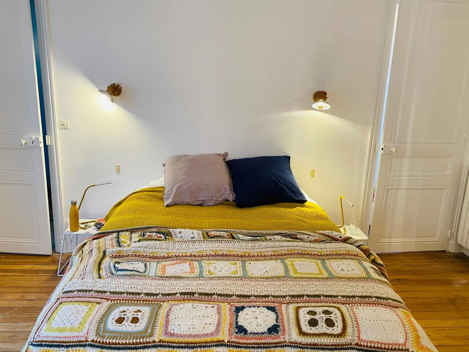 Chambre avec lit, plaid coloré et parquet ancien