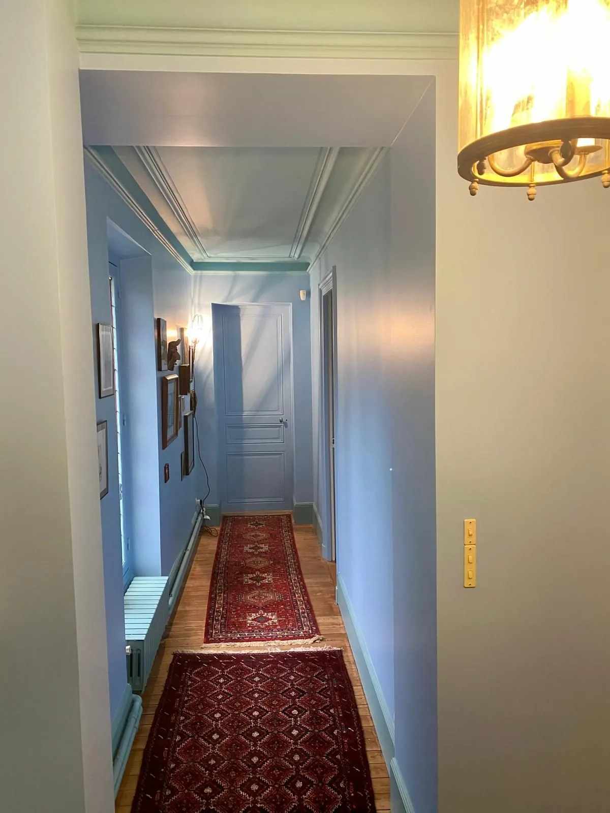 Couloir bleu avec tapis rouge et appliques