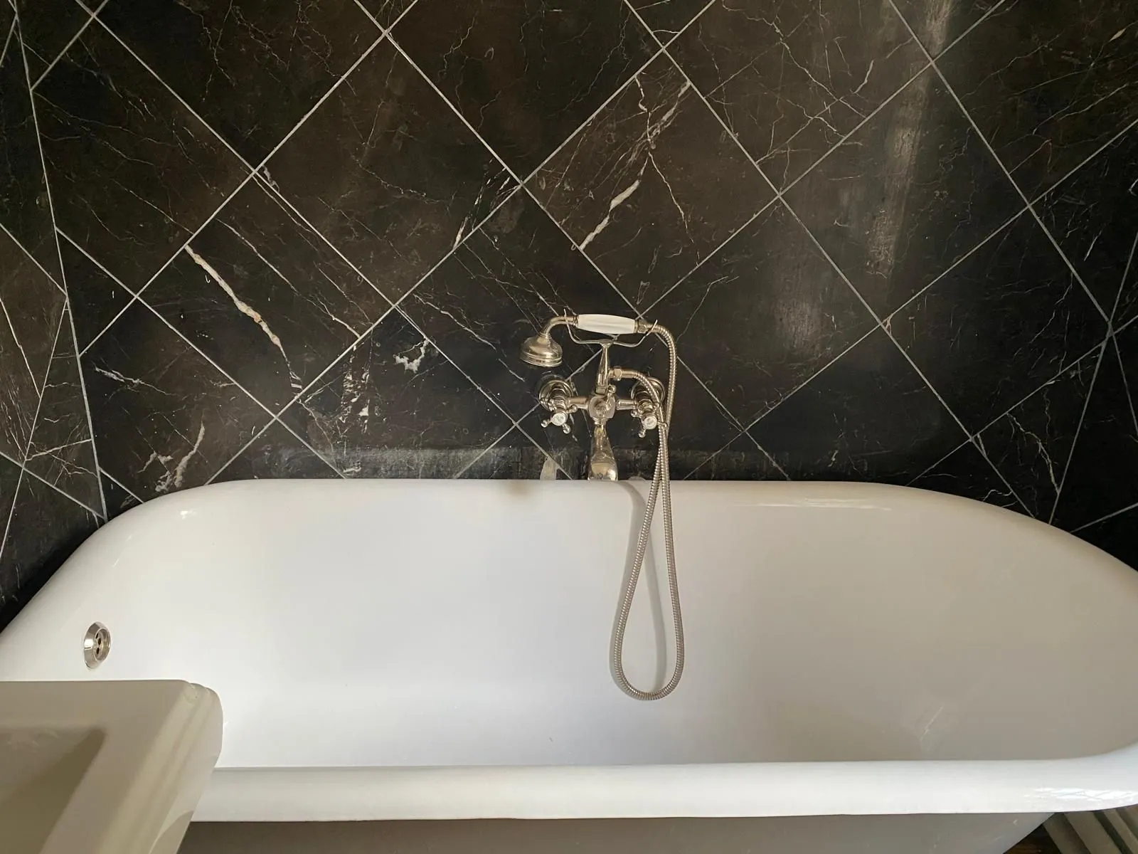 Salle de bains avec baignoire sur pieds et carrelage noir posé en diagonale