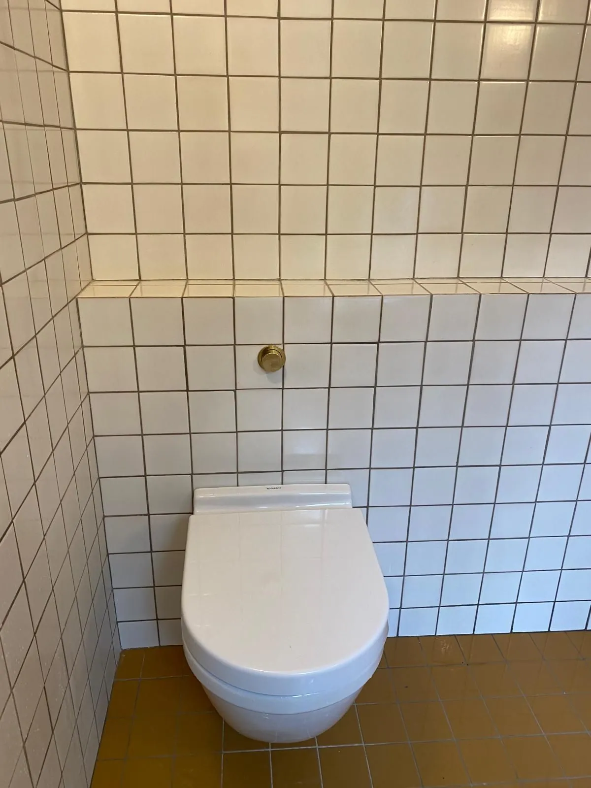 WC suspendu avec carrelage blanc à joints foncés