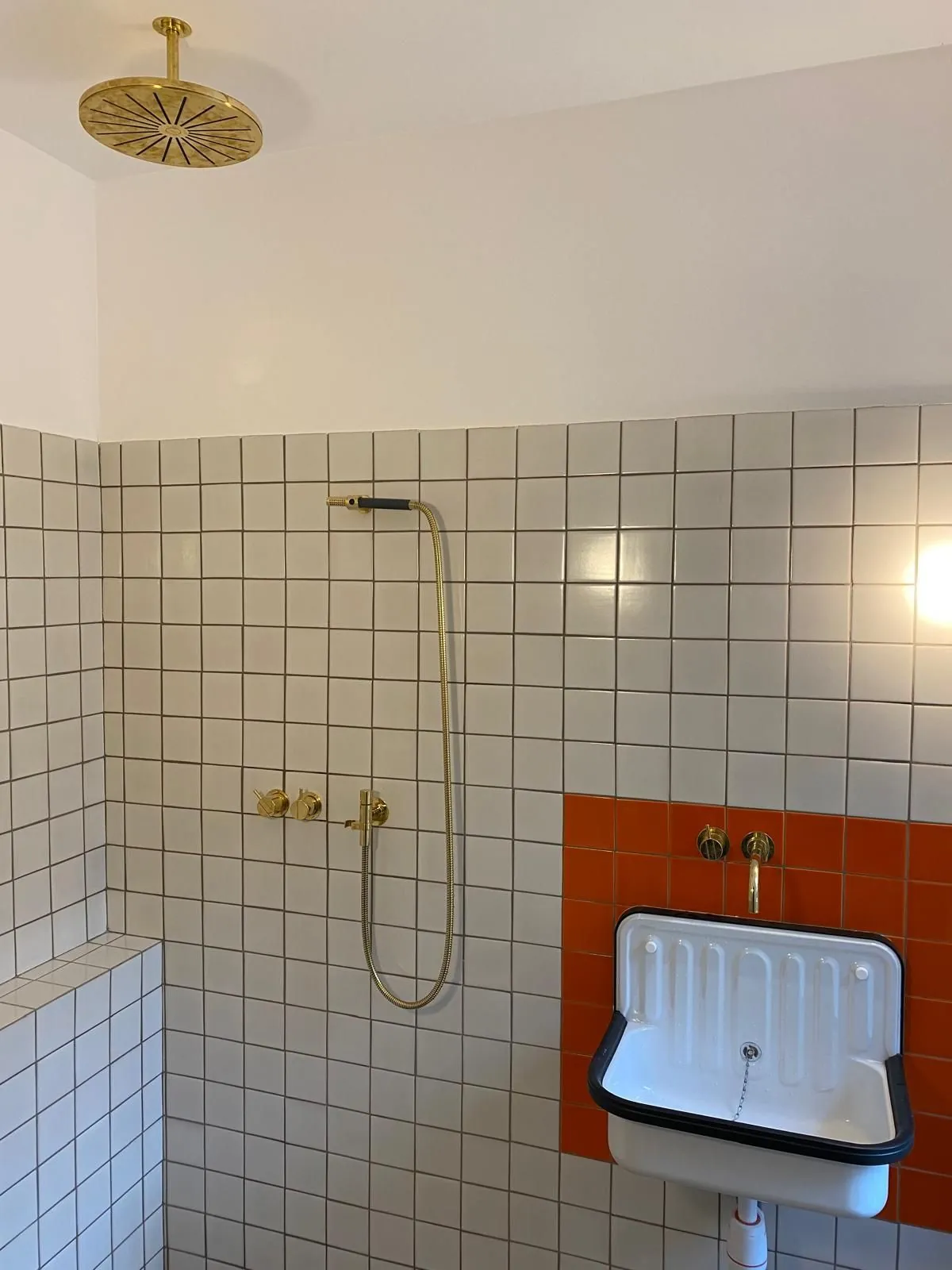 Douche avec robinetterie dorée et petit évier en émail