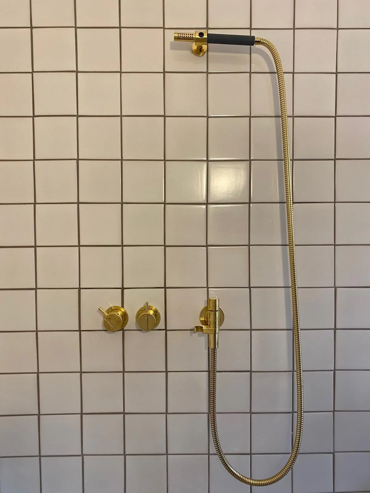 Douche avec robinetterie dorée et carrelage blanc