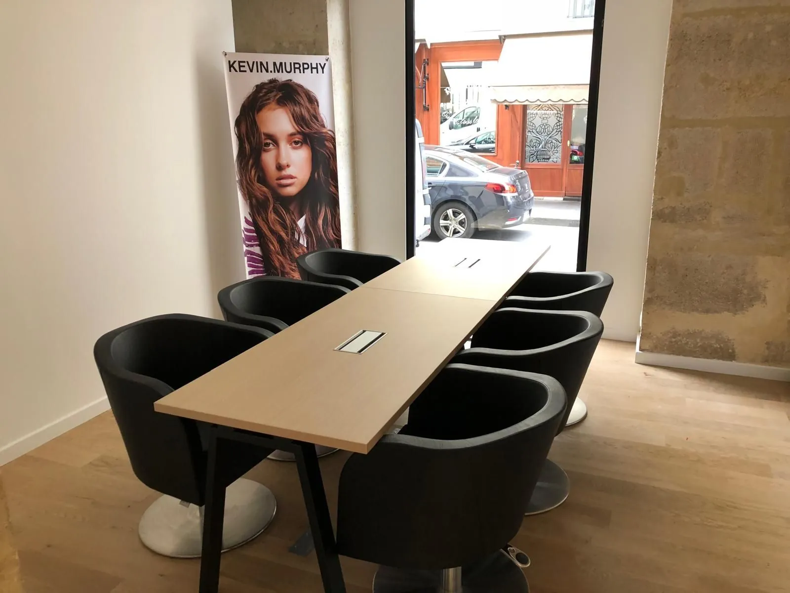 Table de travail avec fauteuils noirs et affiche de coiffure