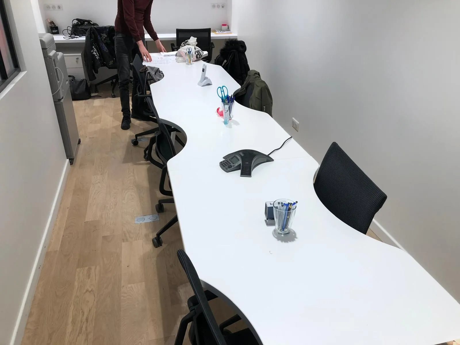 Grande table blanche et chaises noires dans une salle de travail