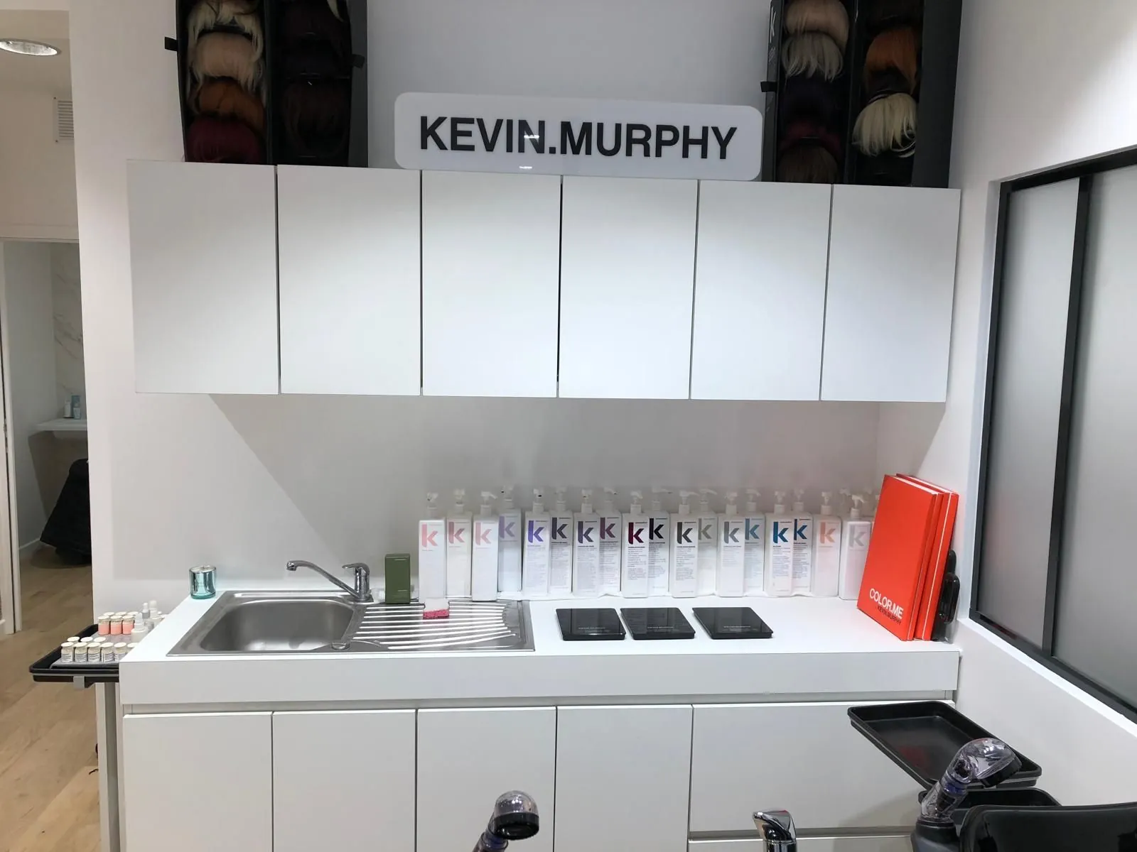 Meuble blanc avec évier et produits de coiffure, verrière à droite