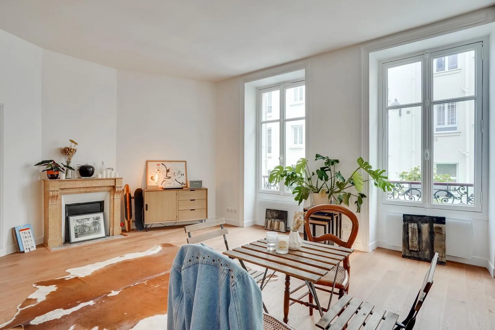 Séjour avec cheminée, buffet en bois et fenêtres sur cour
