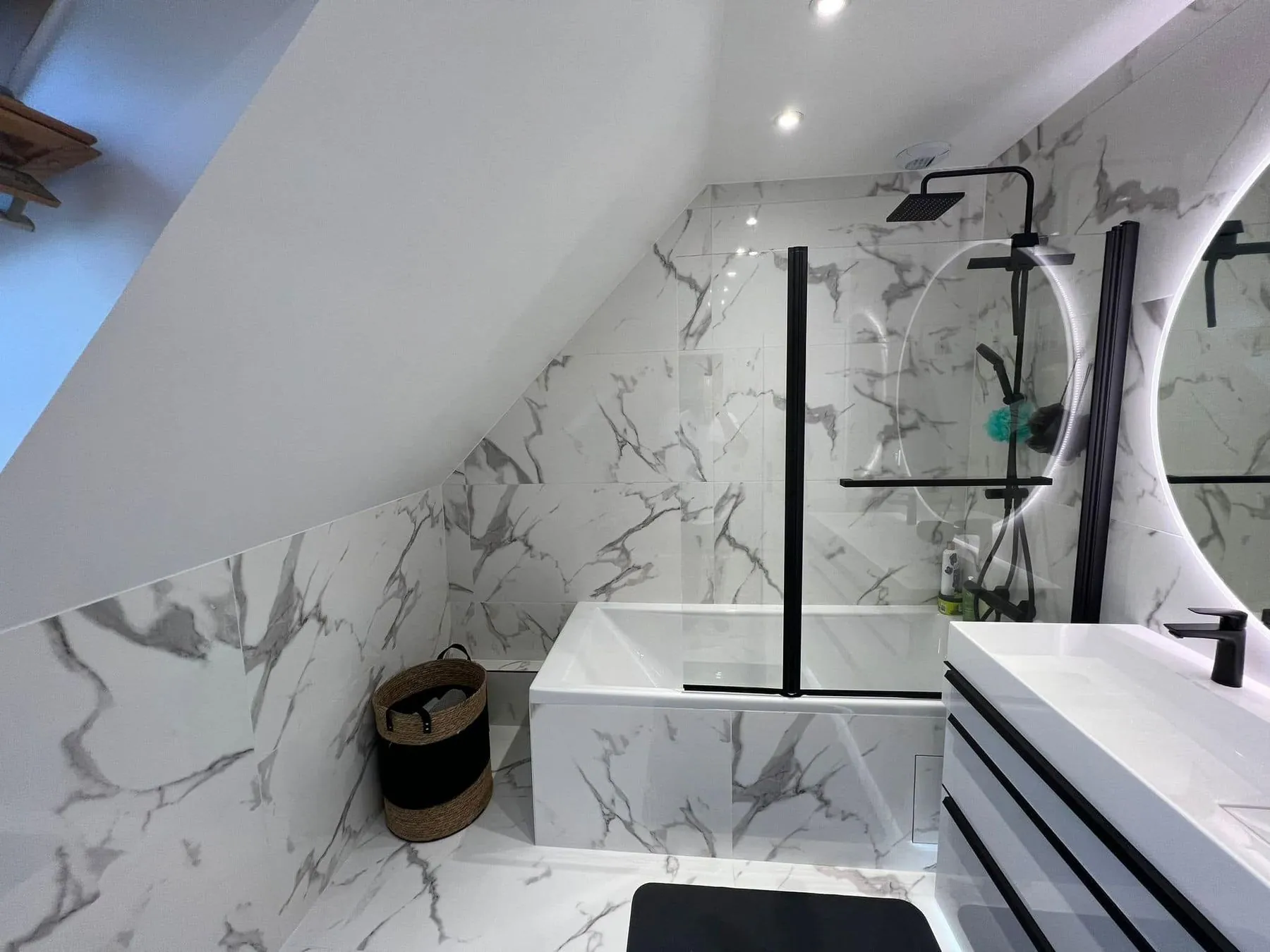 Salle de bain après travaux : faïence effet marbre, baignoire et meuble vasque noir