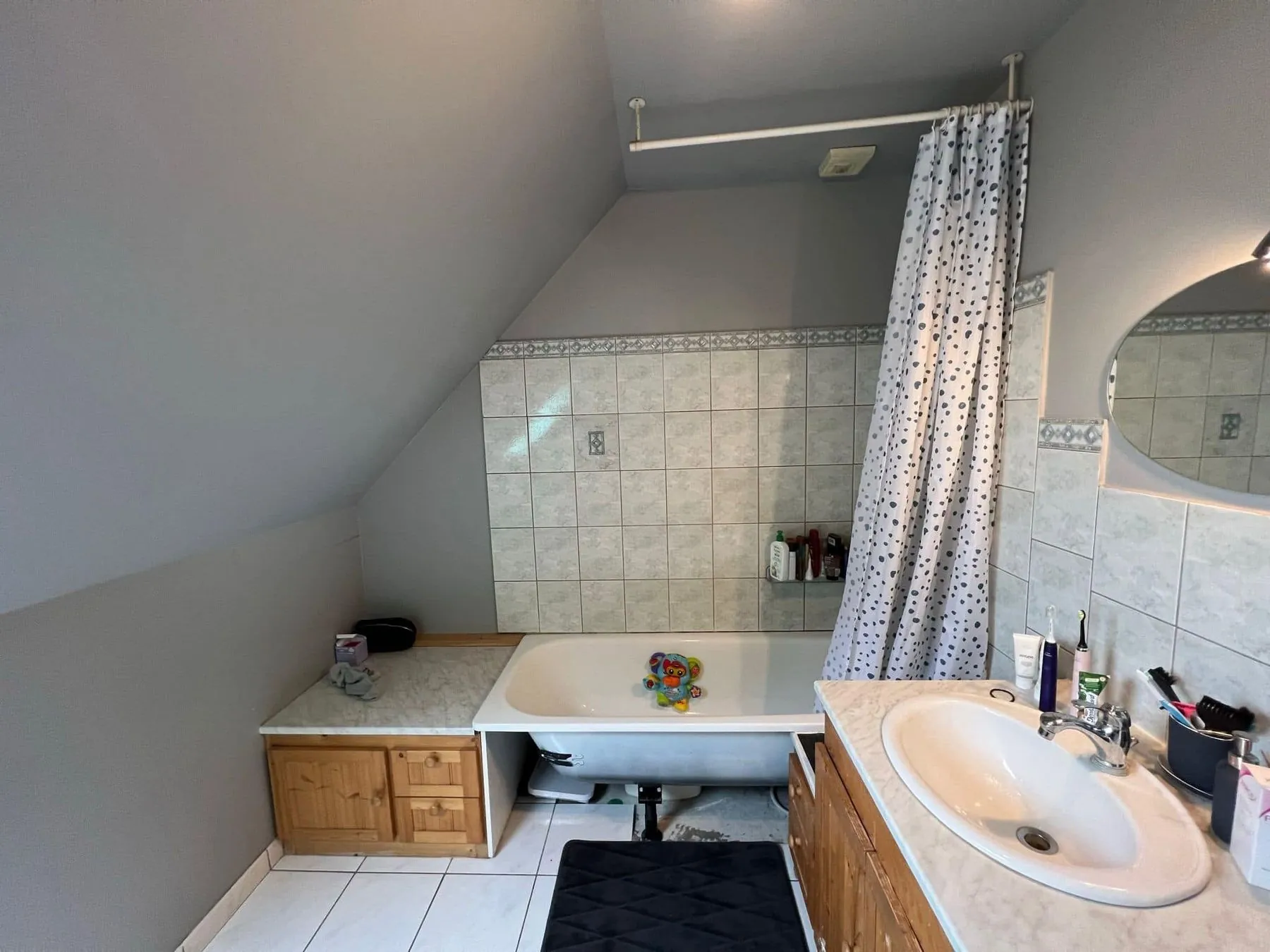 Salle de bain avant travaux : ancienne baignoire, carrelage et meuble en bois